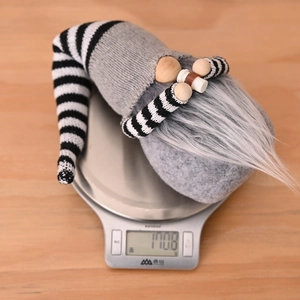 Close-up of a Christmas gnome doll on an electronic scale weighing 110.8g for decoration