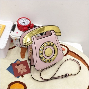 Detail of pink retro telephone crossbody bag with gold dial and receiver features