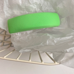 Detail view of a bright green rectangle fabric hair clip with a fine twill texture finish