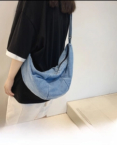Detail of light blue denim hobo bag with adjustable strap and zipper closure