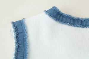 Détail d'une robe en tricot sans manches avec bordure en denim et bords effilochés