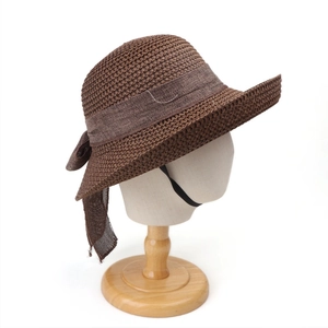 Detail of dark brown straw hat featuring a woven texture and elegant mesh bow accent