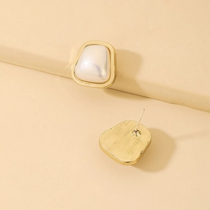 Detailed view of geometric trapezoid gold earrings with white inlay and brushed metal finish