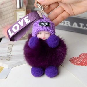 Detail of a purple fox fur baby doll keychain with a knit hat and LOVE ribbon strap