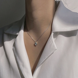 Detailed view of an 8-point star necklace featuring a light blue topaz stone on silver chain