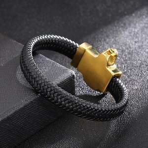 Detail of a men's braided leather bracelet featuring a golden lion head metal clasp