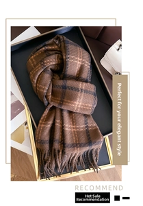Detail of soft cashmere-like scarf with classic dark brown plaid pattern and fringe trim