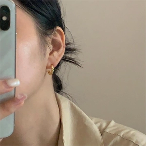 Close-up of golden twist hoop earrings worn in a lifestyle mirror selfie setting