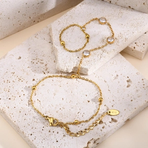 Detail of gold hand chain with round zircon stones on natural stone pedestal