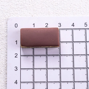 Macro shot of miniature chocolate biscuit charm on a measuring mat for size reference