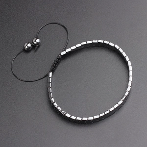 Close-up of geometric hematite beads with adjustable black woven cord on grey background