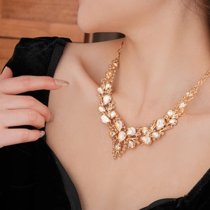 Close-up of golden necklace featuring teardrop opals and rhinestones on model