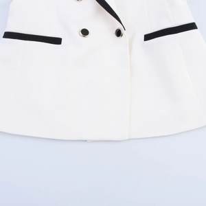 Close-up of white vest suit detailing double-breasted buttons and black trim finish