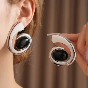 Modern vintage silver spiral earrings featuring a bold black oval cabochon stone on model