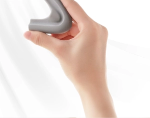 Flexible grey silicone L-shaped corner protector for baby safety shown being bent by hand