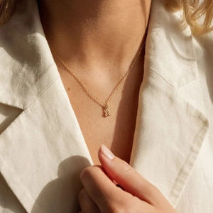 Détail d'un collier pendentif zodiaque doré avec symbole Lion sur mannequin en lin