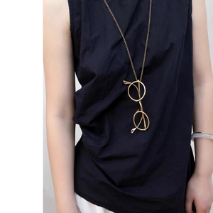 Detail view of a gold eye-shaped pendant necklace styled with dark blue clothing