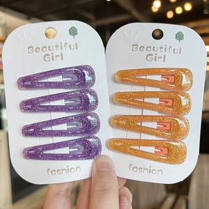 Detail of glitter acrylic snap hair clips in purple and orange on display card
