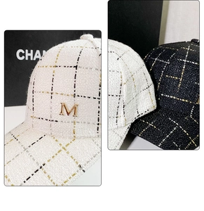 Close-up of tweed plaid baseball caps in black and white with golden metal M logo