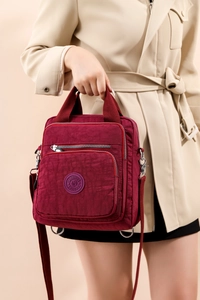Détail du sac bandoulière en nylon bordeaux avec plusieurs zips et sangle réglable