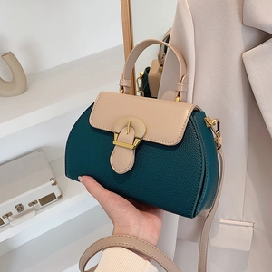 Detailansicht der Handtasche in Kontrastfarben mit dunkelgrünem Leder und Goldschnalle