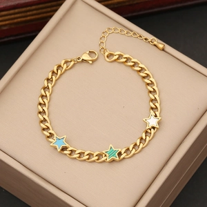 Golden chain bracelet with blue, green and white star pendants on a jewelry box