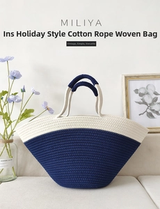 Detail view of woven cotton rope beach bag in navy and cream with round handles