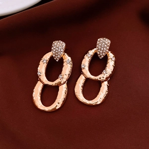 Detailed view of golden double-loop earrings with hammered texture and clear zircons