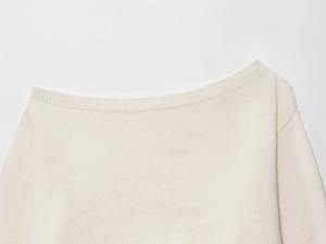 Detail of off-white knitted sweater showing wide off-shoulder neckline and ribbed texture