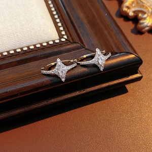 Detailed close-up of starburst hoop earrings with pave cubic zirconia on a wooden frame