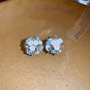 Gros plan détaillé de boucles d'oreilles sphériques à fleurs bleues et blanches à strass