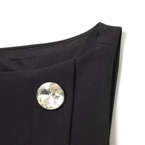 Top sans manches noir avec grand bouton en strass étincelant au niveau du décolleté