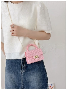 Detail view of a pink PVC jelly bag with quilted pattern and pearl handle on a model