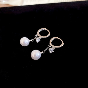 Detail of silver pearl tassel earrings with zircons on a black velvet background