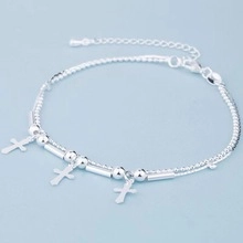 Macro detail of a 925 sterling silver double-layer chain anklet with cross charms