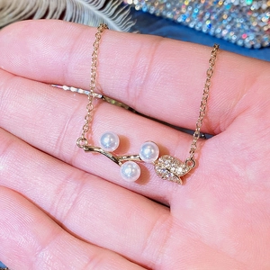 Detailed macro view of gold branch pendant with three white pearls and cubic zirconia leaf