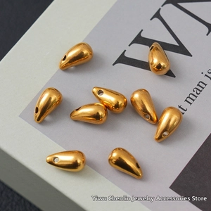 Detailed view of polished golden waterdrop-shaped stainless steel beads for DIY jewelry