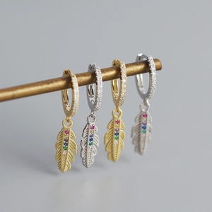 Dettaglio di orecchini a piuma in oro e argento con pietre di zircone colorate