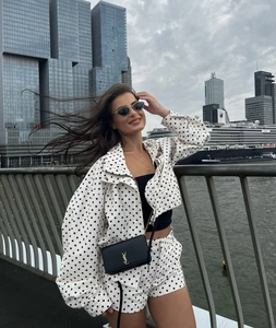Detail von weißem Polka-Dot-Jacke-Set mit Shorts und eleganter schwarzer Kettentasche