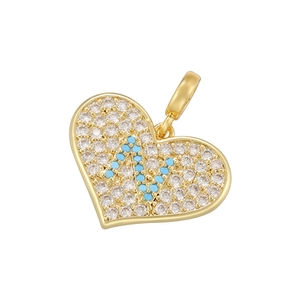 Macro detail of gold heart pendant with micro-paved crystals and turquoise letter N