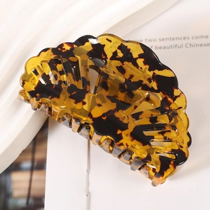 Macro detail of shell-shaped acetate hair claw with amber tortoise shell texture