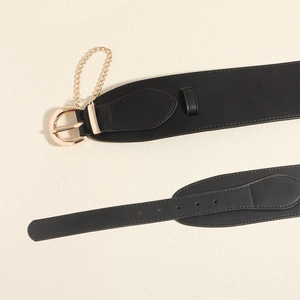 Detail of black leather corset belt featuring gold metal buckle and decorative gold chain