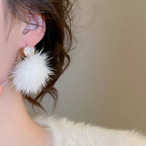 Détail d'une boucle d'oreille pompon blanc avec zircon sur une femme mannequin
