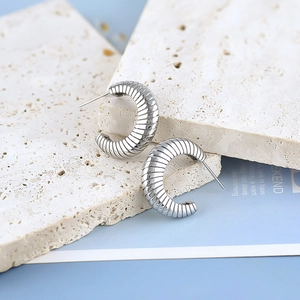 Silver ribbed C-shaped earrings with spiral texture on light beige stone base