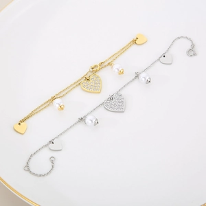 Detail view of heart-shaped pendants on gold and silver chain bracelets with white pearls