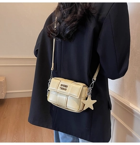 Détail du sac bandoulière beige tressé avec pendentif étoile et bandoulière chaîne