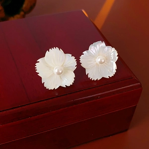 Vue détaillée des boucles d'oreilles fleurs en nacre avec perle sur bois sombre