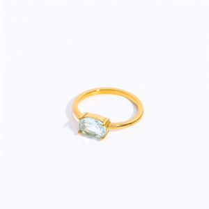 Macro detail of gold stainless steel ring featuring an oval light blue zircon stone