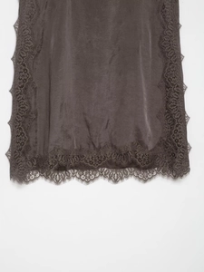 Detail view of smooth dark grey satin fabric with delicate lace trim on the hem
