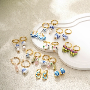 Macro detail of blue and white porcelain earrings with gold rings and pearls